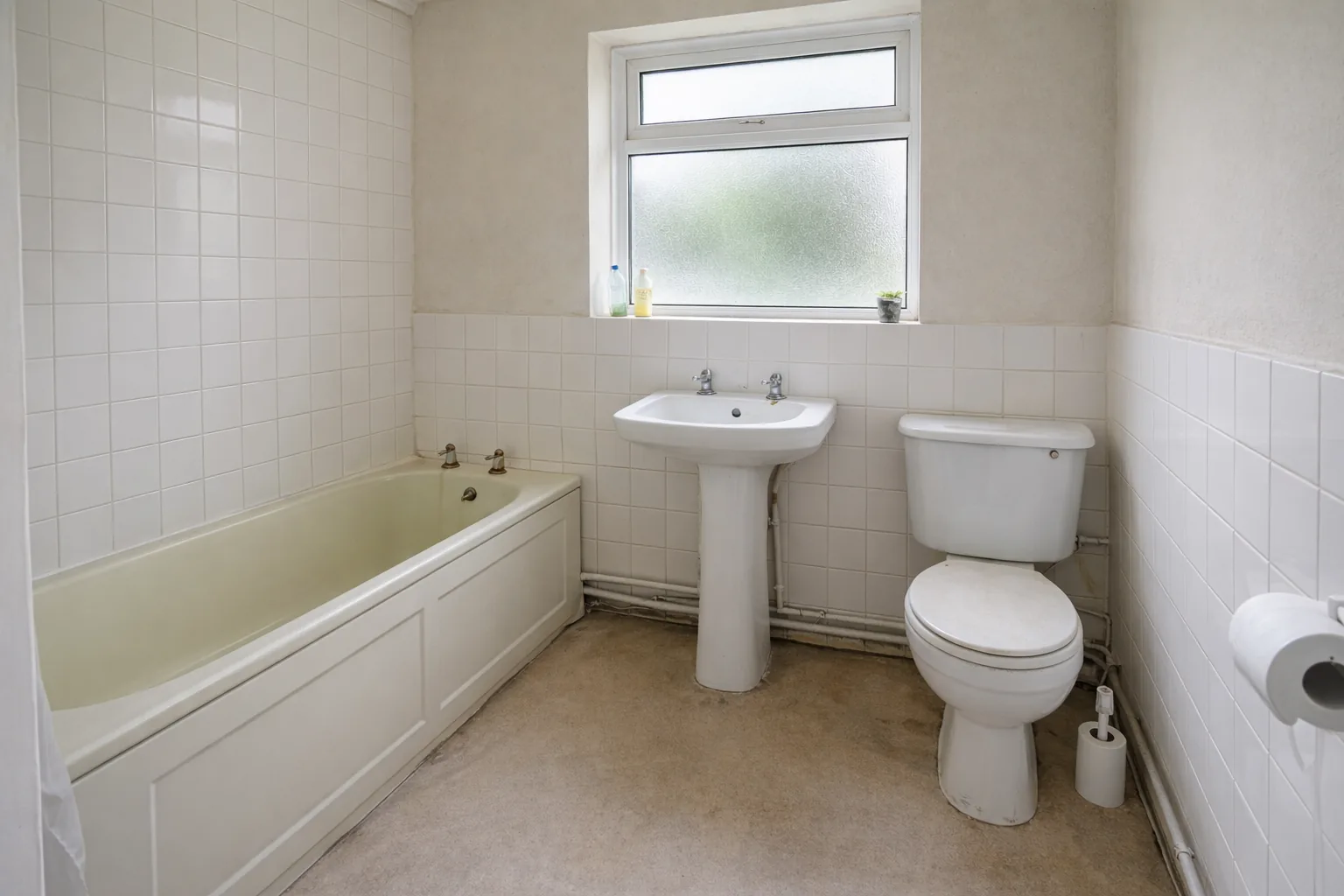 Bathroom before renovation: dated white suite with bath