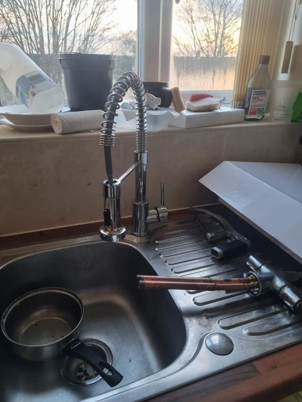 Plumber mid-installation fitting a new kitchen sink and pull-out mixer tap