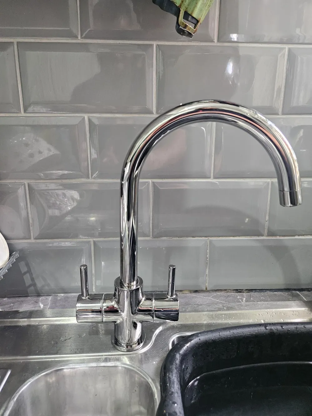 New chrome swan neck mixer tap fitted on a stainless steel kitchen sink by First Call Home Services
