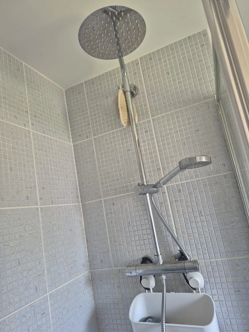 Rainfall shower head and thermostatic riser fitted in a grey mosaic tiled shower