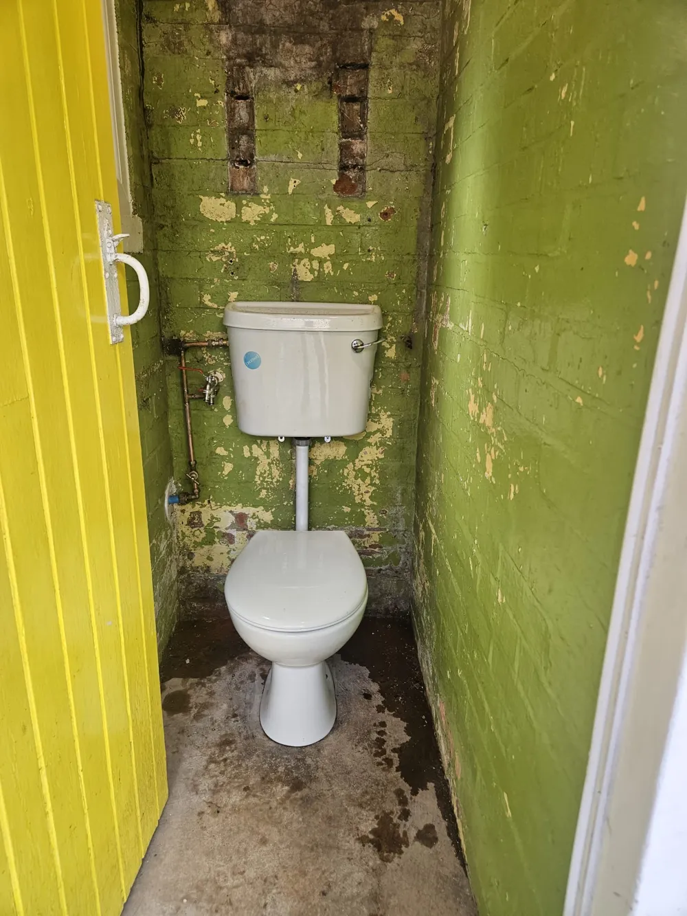 New modern white close-coupled toilet fitted after replacement in a Coventry outdoor WC