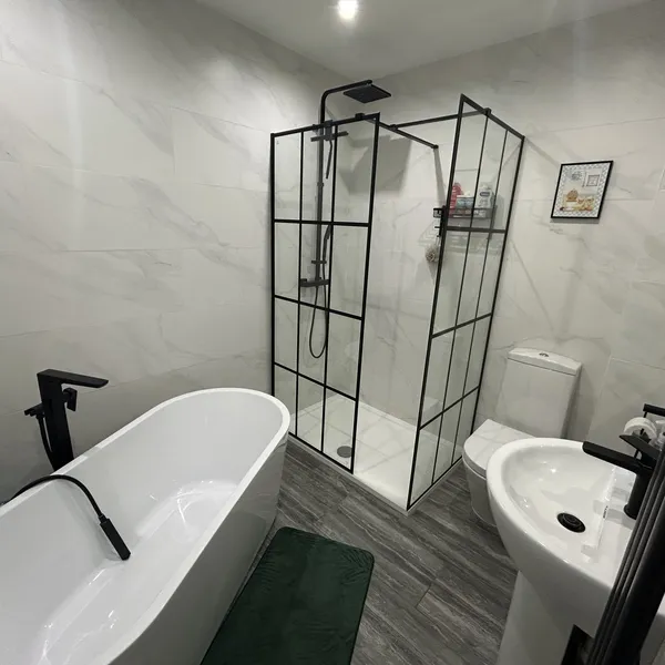 Freestanding bath with a black-framed shower screen in a Coventry bathroom